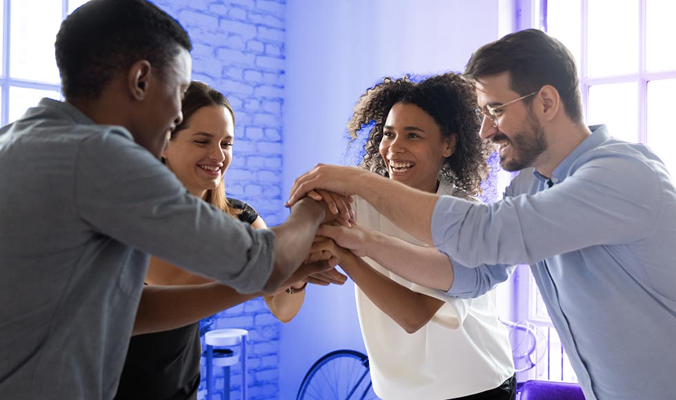 A team of professionals collaborating and celebrating success in a modern workspace, symbolizing innovation, technology transformation, and strategic business solutions.